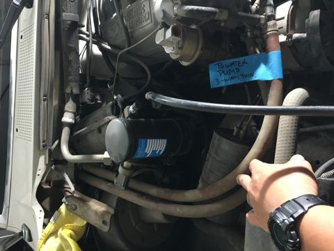 1987 Ford Bronco - A close-up view of an engine bay with a blue sticky note attached to a hose. The note reads "TO WATER PUMP 3-WAY THIN".