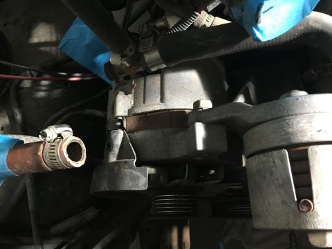 1987 Ford Bronco - Close-up view of the engine bay of a 1987 Ford Bronco, showing a belt tensioner assembly and hoses secured with hose clamps. Blue tape is v…
