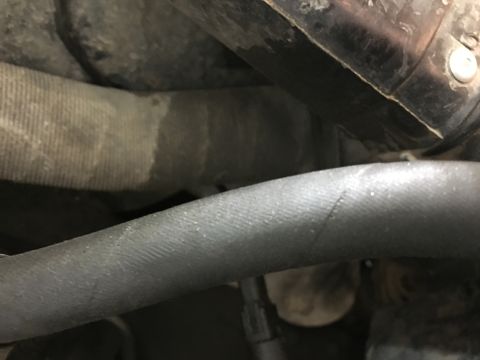 1987 Ford Bronco - A close-up view of two rubber hoses in an engine bay, likely part of the cooling system. One hose is ribbed and tan, while the other is smo…