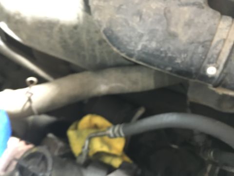 1987 Ford Bronco - A close-up view of engine components in a vehicle, showing various hoses and a yellow rag. The image focuses on the mechanical parts with a…
