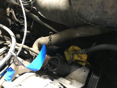 1987 Ford Bronco - A close-up view of engine components in a vehicle, featuring a power steering hose secured with a yellow rag and blue tape applied to a met…