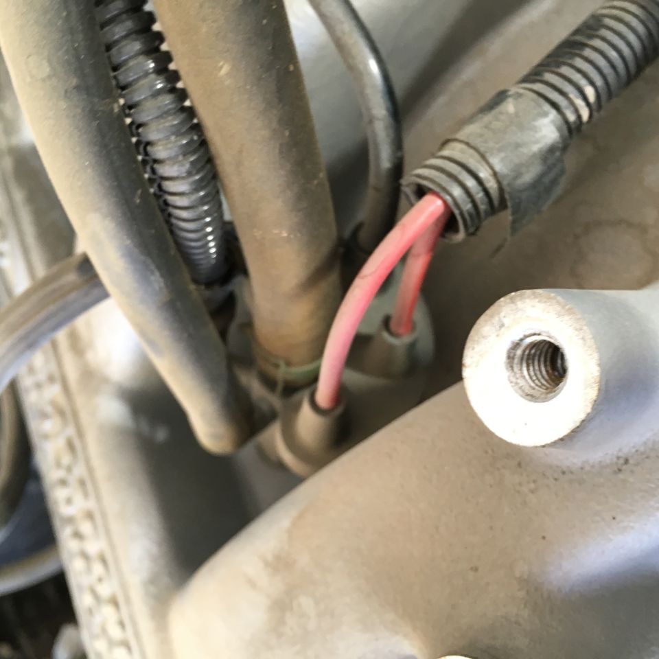 Red wires coming out of black conduit near a threaded metal boss.
