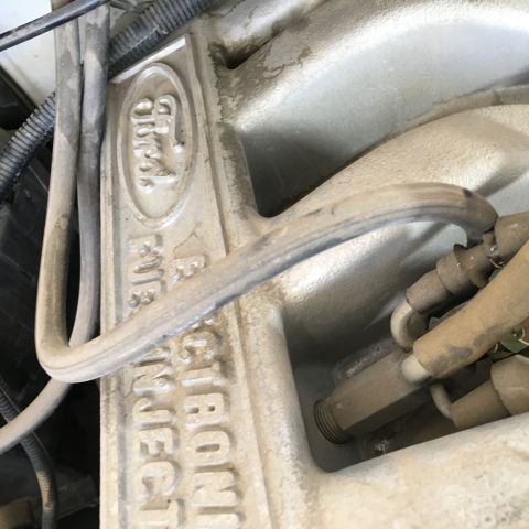 1987 Ford Bronco - Close-up view of the intake manifold on a Ford engine, featuring the embossed "Ford" logo and "Fuel Injection" text. Several fuel lines and…