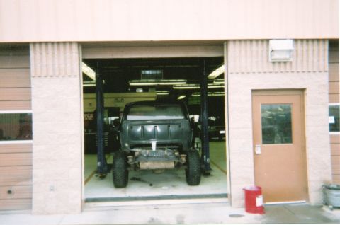 1978 Ford Bronco - A truck chassis is elevated on a lift within a garage bay, awaiting further work.