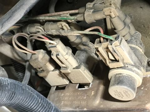 1987 Ford Bronco - A close-up view of dusty electrical connectors and wiring harness components, likely from a vehicle's engine bay. The connectors are beige…