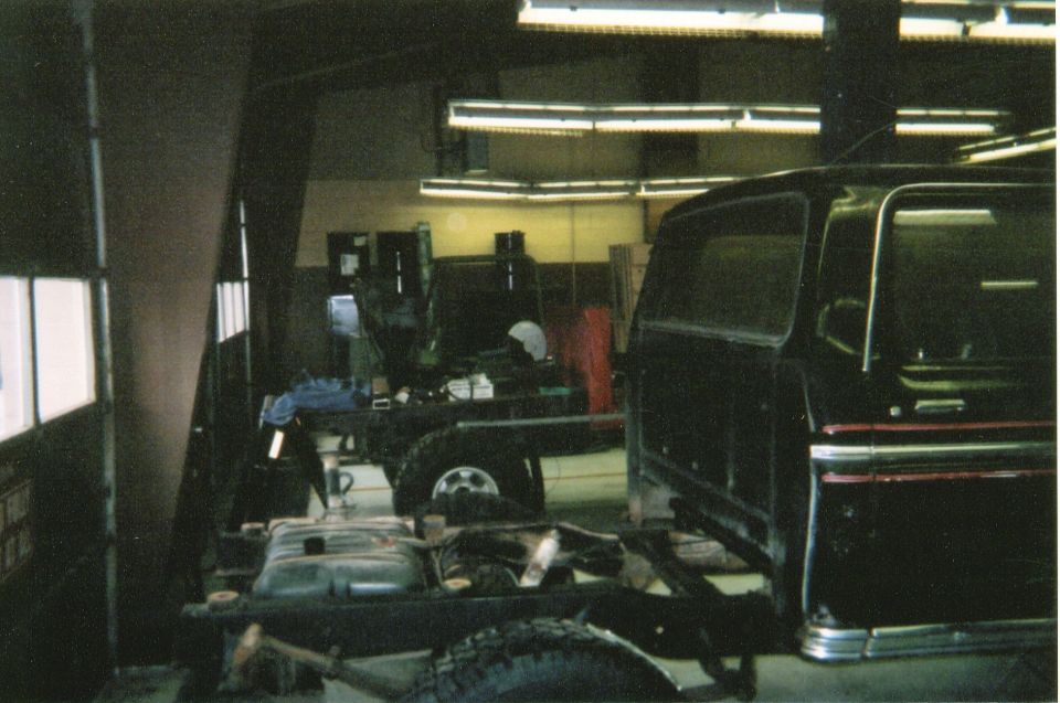 Black Ford Bronco body on a chassis with the fuel tank visible, in a workshop