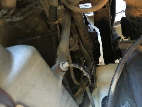 1987 Ford Bronco - A close-up view of the underside of a vehicle, showing various hoses, wires, and metal components. A sensor with a wire is visible attached…