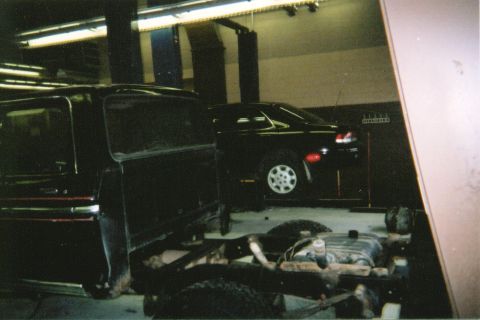 1978 Ford Bronco - Two vehicles are in a garage, one appears to be undergoing repair or modification.