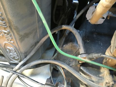 1987 Ford Bronco - A close-up view of engine components in a vehicle, showing various wires, hoses, and a section of the engine block with visible text that a…