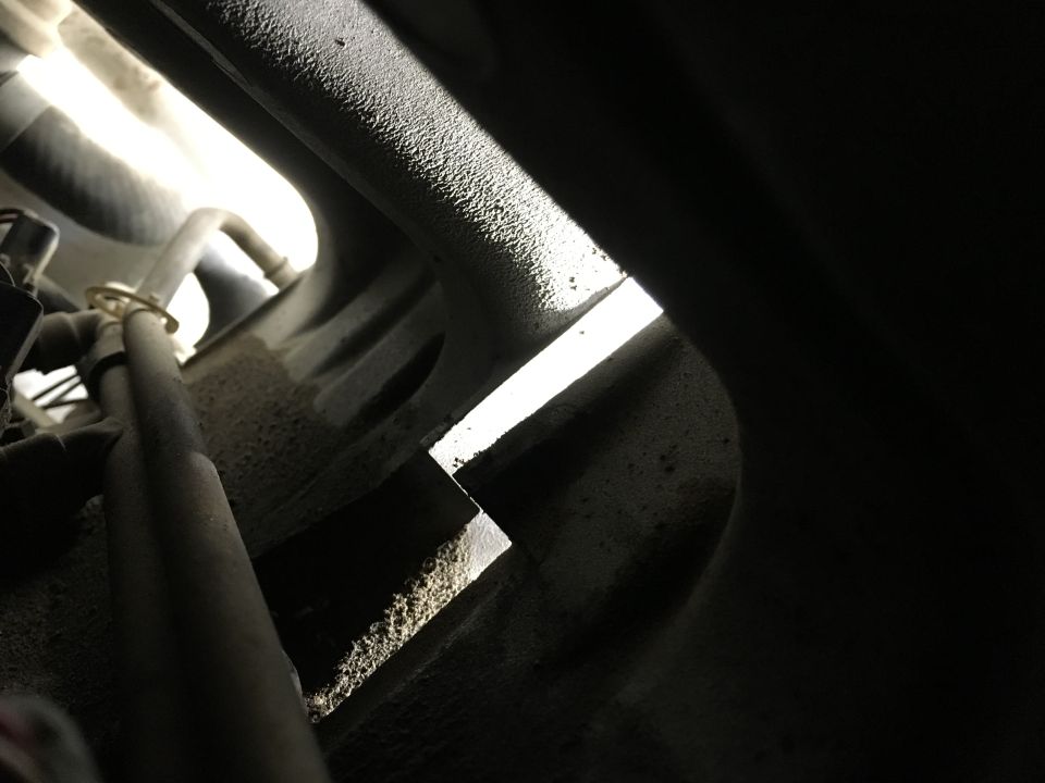 Close-up of a metal bracket in an engine bay with dust and grime.