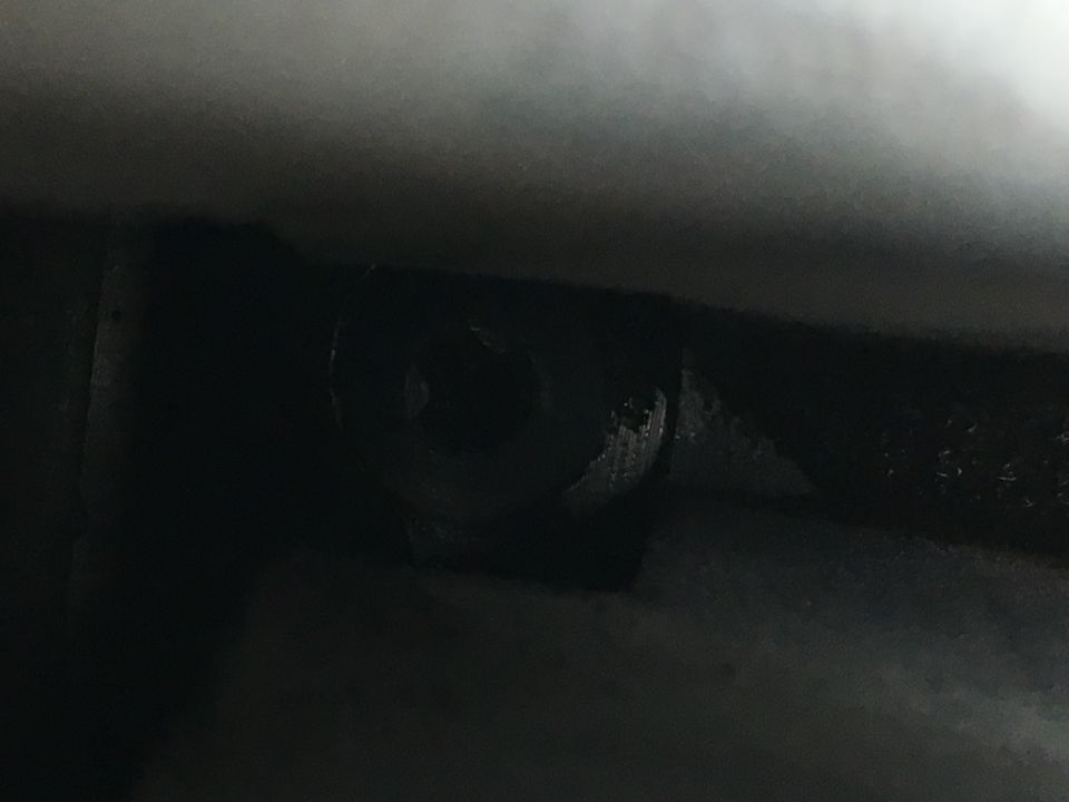 Close-up of a worn bolt head in a dark metal surface.