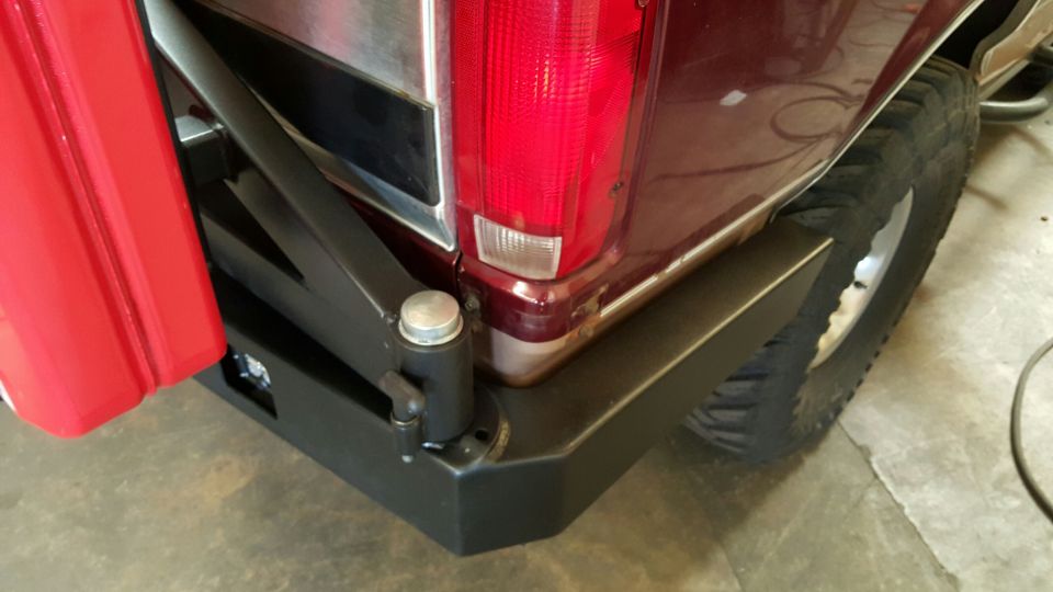 Rear corner of a red SUV with custom black bumper and red fender flare.