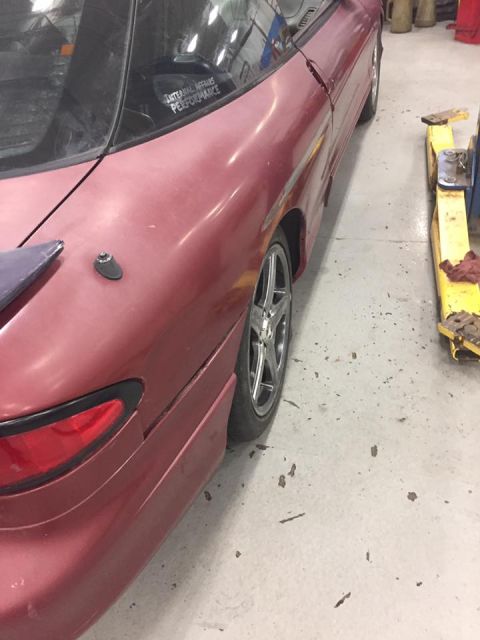 1995 Ford Probe - The rear passenger side of a red 1995 Ford Probe is shown in a garage setting. A sticker on the rear window reads "INTERNAL AFFAIRS PERFORM…