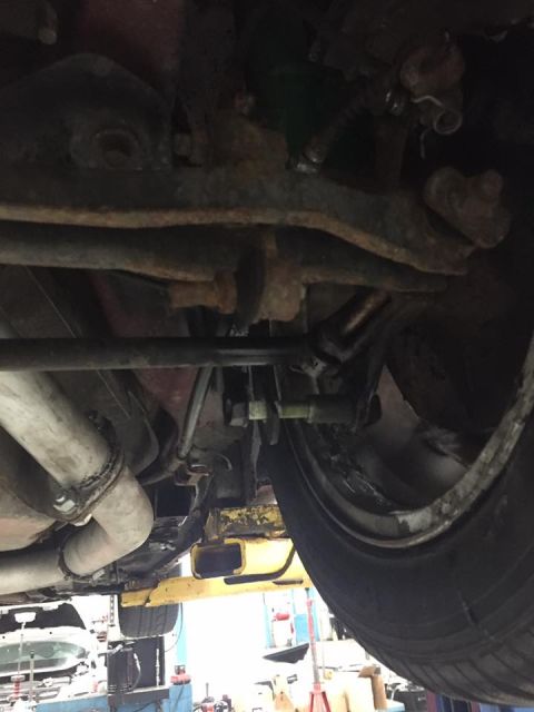 1995 Ford Probe - The underside of a vehicle is shown, with the exhaust system, suspension components, and a tire visible. The vehicle appears to be on a lif…