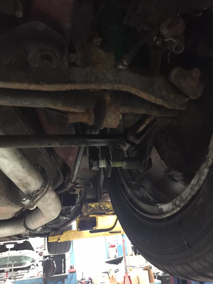 Underside of a vehicle showing suspension, exhaust, and tire.
