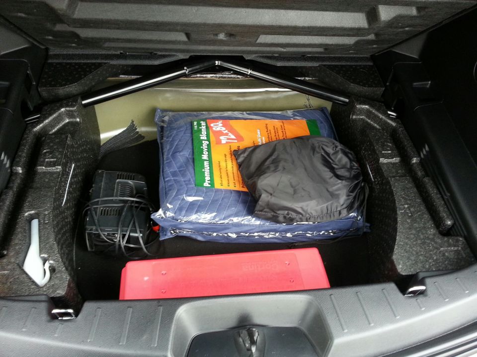 Trunk of a 2016 Ford Explorer with moving blanket, bag, charger, and reflector.