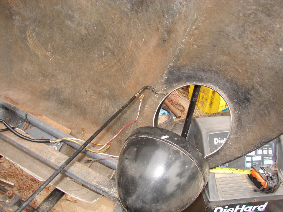 Inside a large hollow structure showing a black headlight, wires, and a DieHard battery charger.