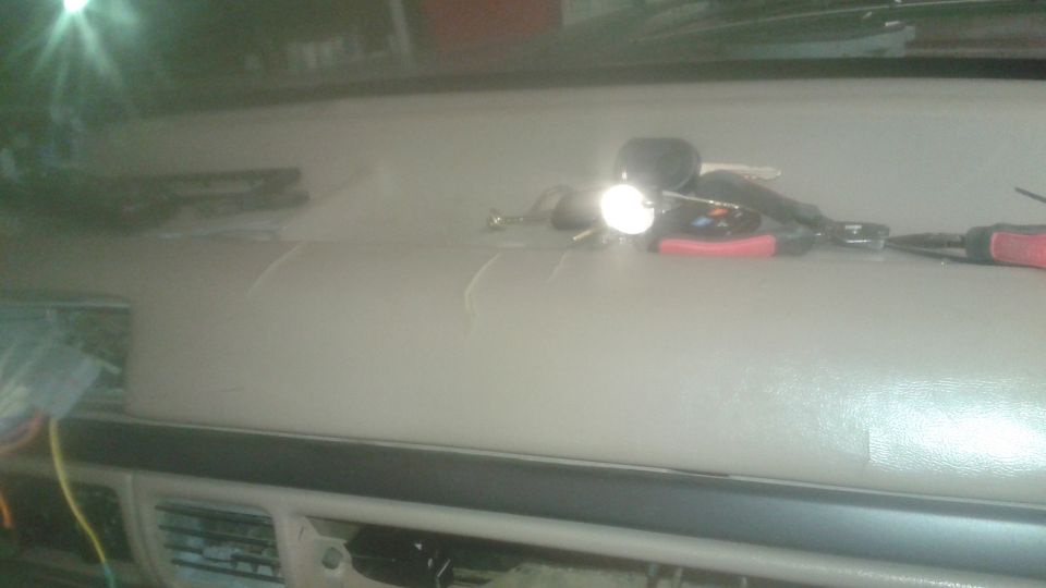 Cracked tan dashboard of a vehicle with keys and tools.