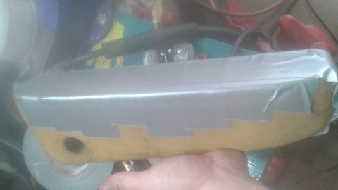 1996 Ford Bronco - A person holds a custom-built part covered in silver and yellow duct tape, likely a modification for a vehicle. The part has a curved shape…