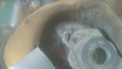 1996 Ford Bronco - A close-up view of a metal part with a threaded hole, possibly part of a vehicle's suspension or drivetrain, showing wear and some debris.