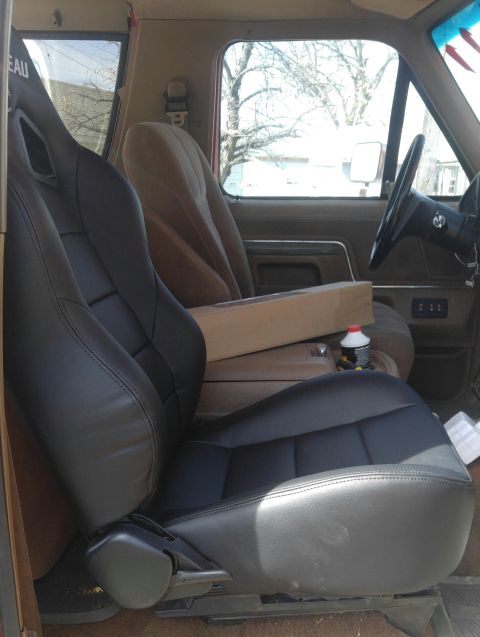 1991 Ford Bronco - The interior of a vehicle shows a new black racing seat installed in the driver's position, with a tan passenger seat visible behind it. A…