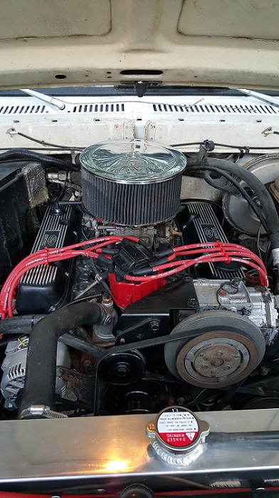 1978 Ford Bronco - Close-up view of the engine bay of a 1978 Ford Bronco, showing the V8 engine with red spark plug wires, a chrome air filter, and a polished…