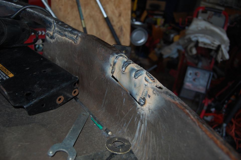 Welded metal part with wrench and black component.