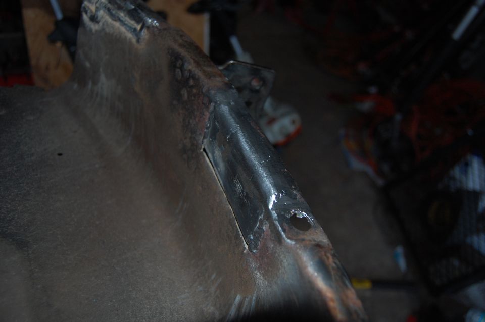 Close-up of a rusty metal bracket with a hole, possibly a vehicle part.