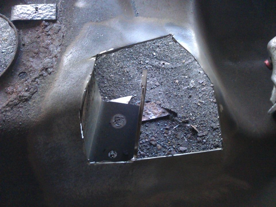 Rusted metal with a cut-out hole filled with dirt and debris.
