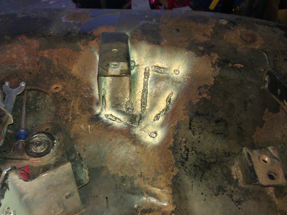 Close-up of rusted metal with fresh welds and hardware.