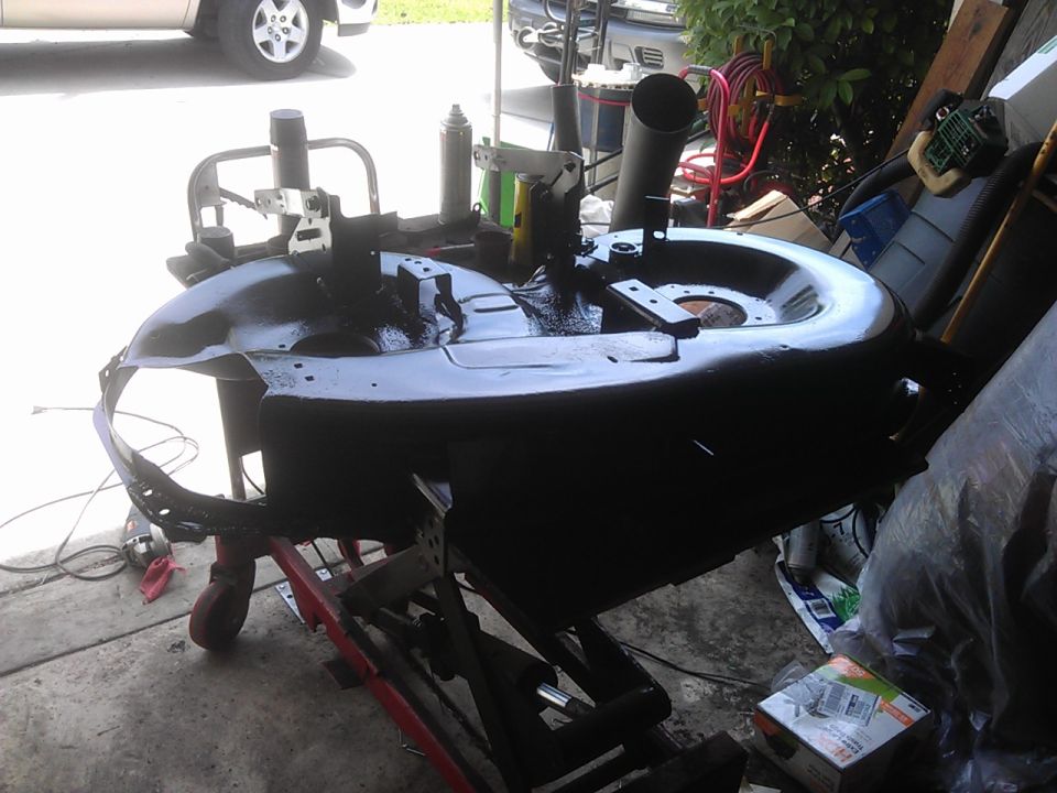 Black mower deck on a red stand with tools in the background.