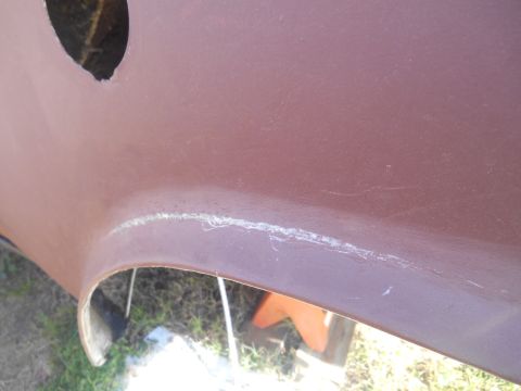 1972 Ford Bronco - Close-up view of the lower body panel of a vehicle, possibly a boat hull, showing a seam with some repair material and scuff marks. The pan…