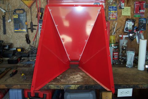 1990 Ford Bronco - A red metal funnel-shaped object with a clear plastic top is sitting on a wooden workbench. The workbench is cluttered with various tools a…