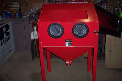 1990 Ford Bronco - A red sandblasting cabinet with two circular gloves on the front is shown in a workshop setting. The cabinet has a clear window on top and…