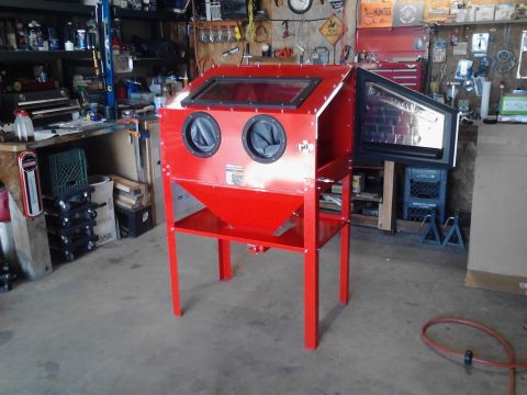 1990 Ford Bronco - A red sandblasting cabinet with two windows and two black gloves is shown in a workshop setting. The cabinet is on a metal stand and has a…