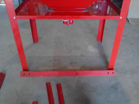 1990 Ford Bronco - The lower section of a red metal stand with four legs and a lower shelf is shown. Several loose red metal pieces are on the concrete floor…