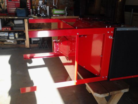 1990 Ford Bronco - A red metal frame structure with black panels sits on a wooden bench in a garage. The structure appears to be a piece of equipment or a cus…