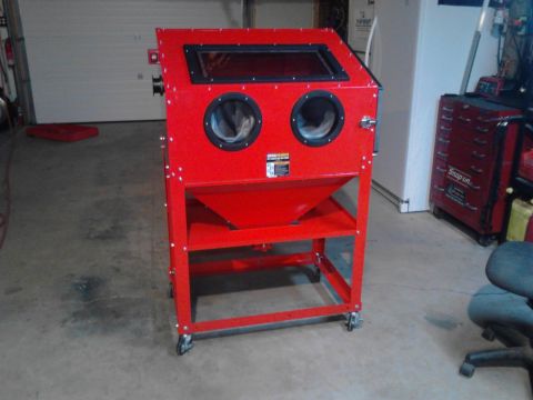 1990 Ford Bronco - A red sandblasting cabinet with two circular openings and a viewing window sits on a wheeled cart in a garage. To the right, a red Snap-on…
