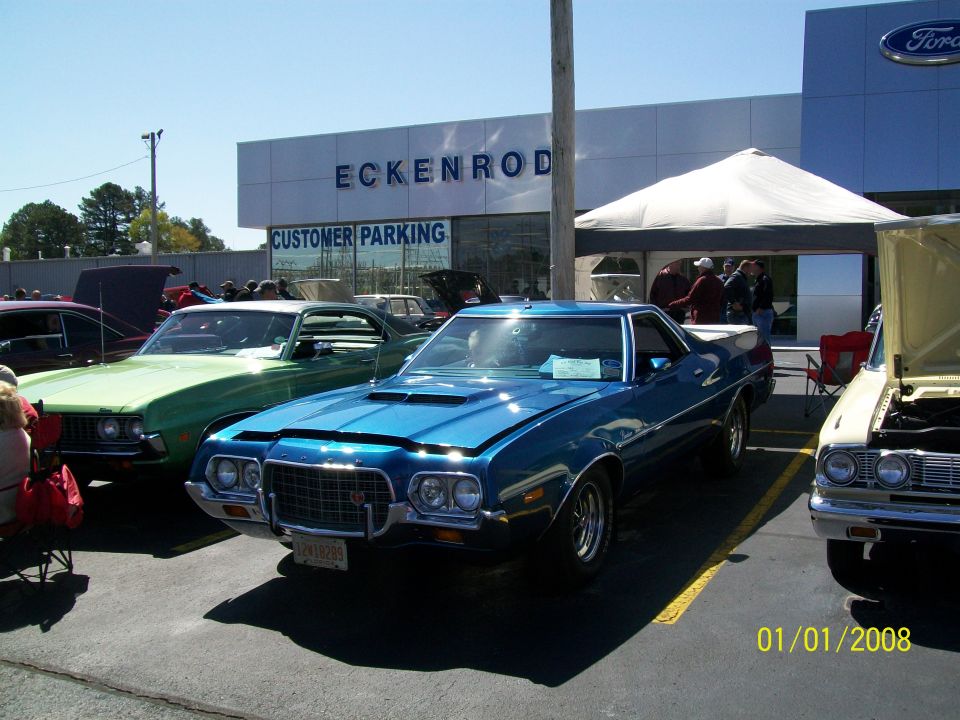 Blue 1966 Ford Ranchero parked in front of a Ford dealership.