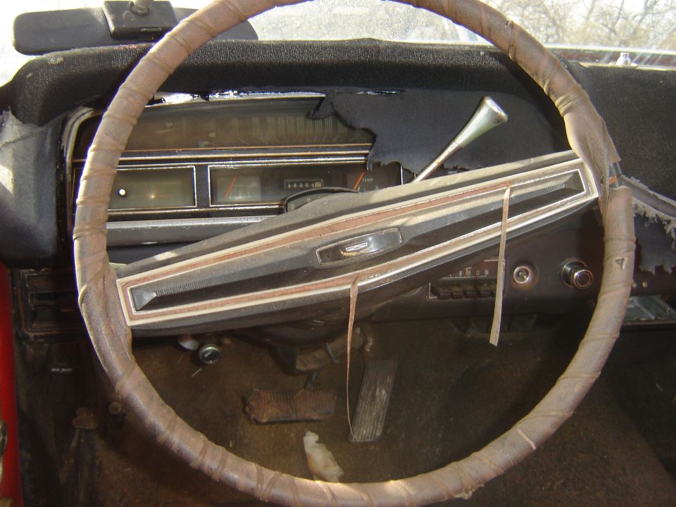 Interior of a vintage car showing a worn steering wheel and dashboard.