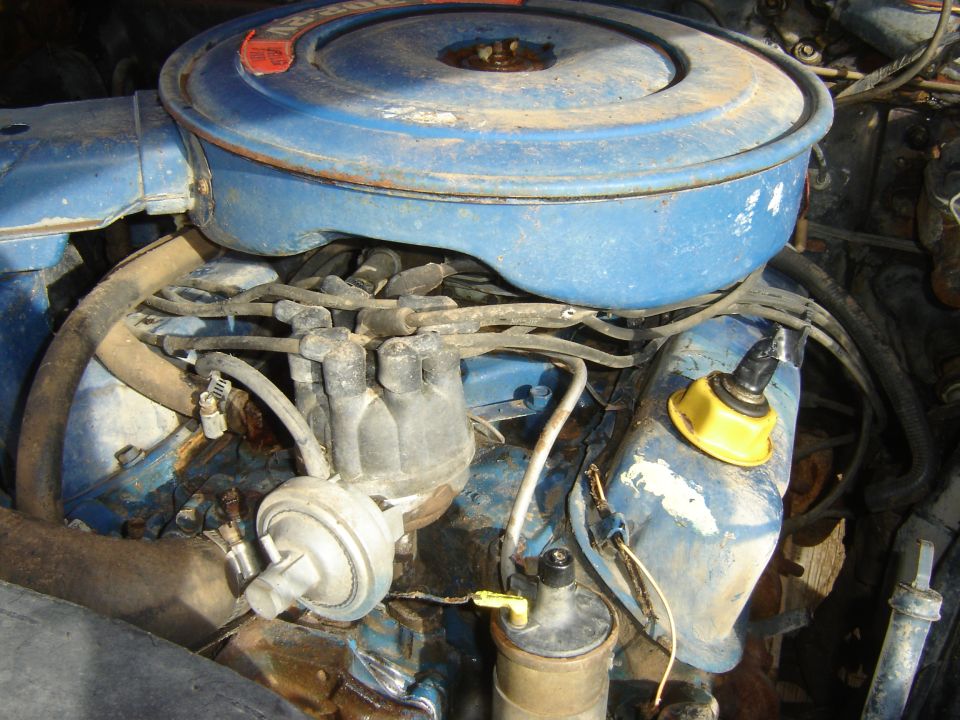 Close-up of a blue engine bay with air cleaner, distributor, and wires.