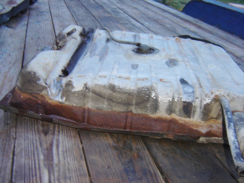 Rusted metal fuel tank with hose and cap on wooden deck