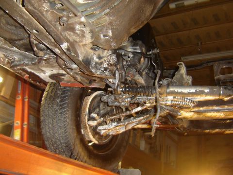 1971 Ford Ranchero - The underside of a vehicle is shown, lifted on an orange lift. The focus is on the front suspension and steering components, which appear h…
