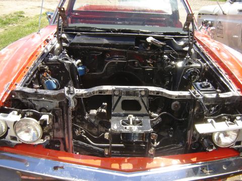 1971 Ford Ranchero - The engine bay of a red 1971 Ford Ranchero is shown with the hood open. The engine and surrounding components appear to be covered in a dar…