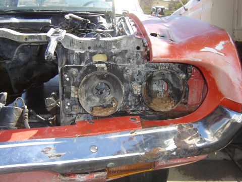 1971 Ford Ranchero - The front end of a red 1971 Ford Ranchero shows significant rust and damage, with the hood open and the grille and headlights removed. The…