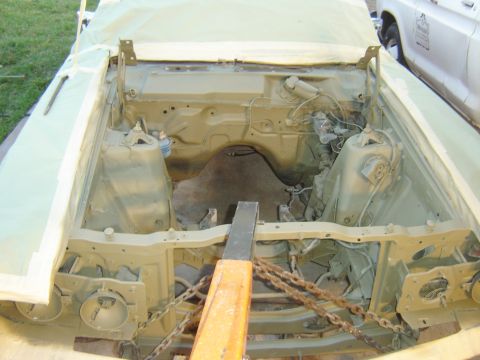 1971 Ford Ranchero - The engine bay of a classic car, likely a 1971 Ford Ranchero, is shown with the engine removed and the chassis painted a light tan color. T…