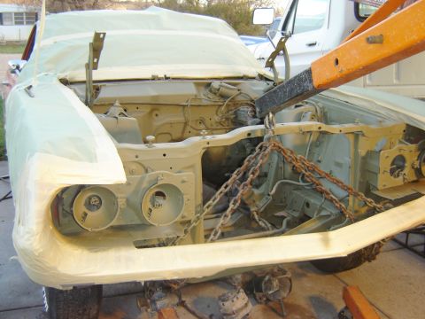 1971 Ford Ranchero - A classic car's front end, likely a Ford Ranchero, is covered in masking paper and primer. An engine hoist with chains is attached to the f…