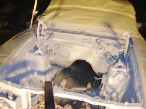 1971 Ford Ranchero - The engine bay of a vehicle is covered in a protective tarp and has been painted white primer. The vehicle appears to be a classic truck or…