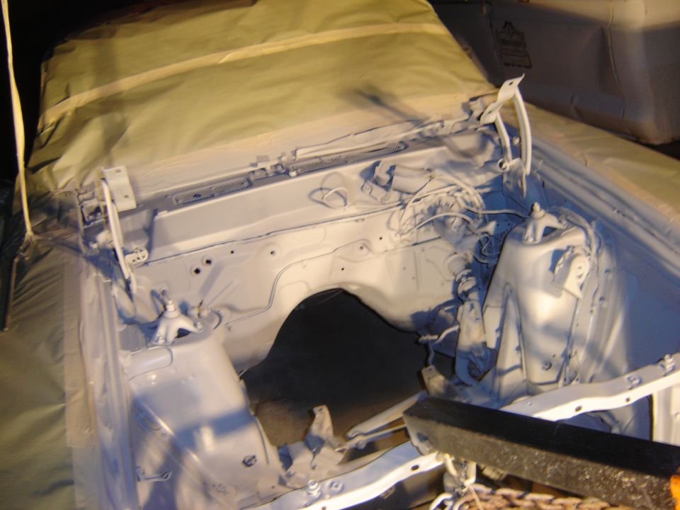 Vehicle engine bay covered in primer and masked off for painting.