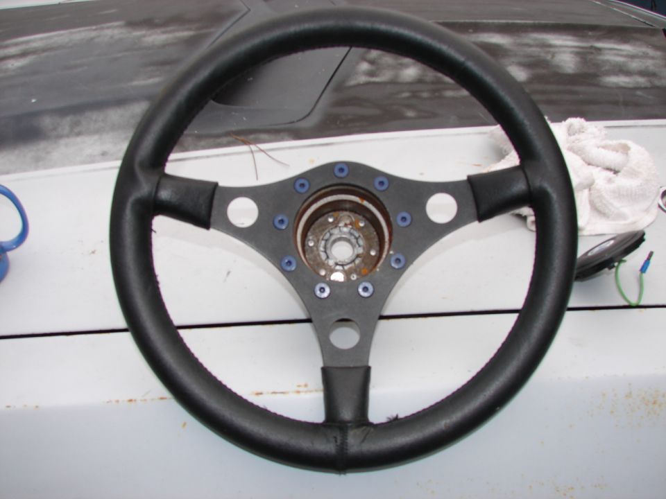 Black aftermarket steering wheel with blue bolt accents and a visible metal hub.